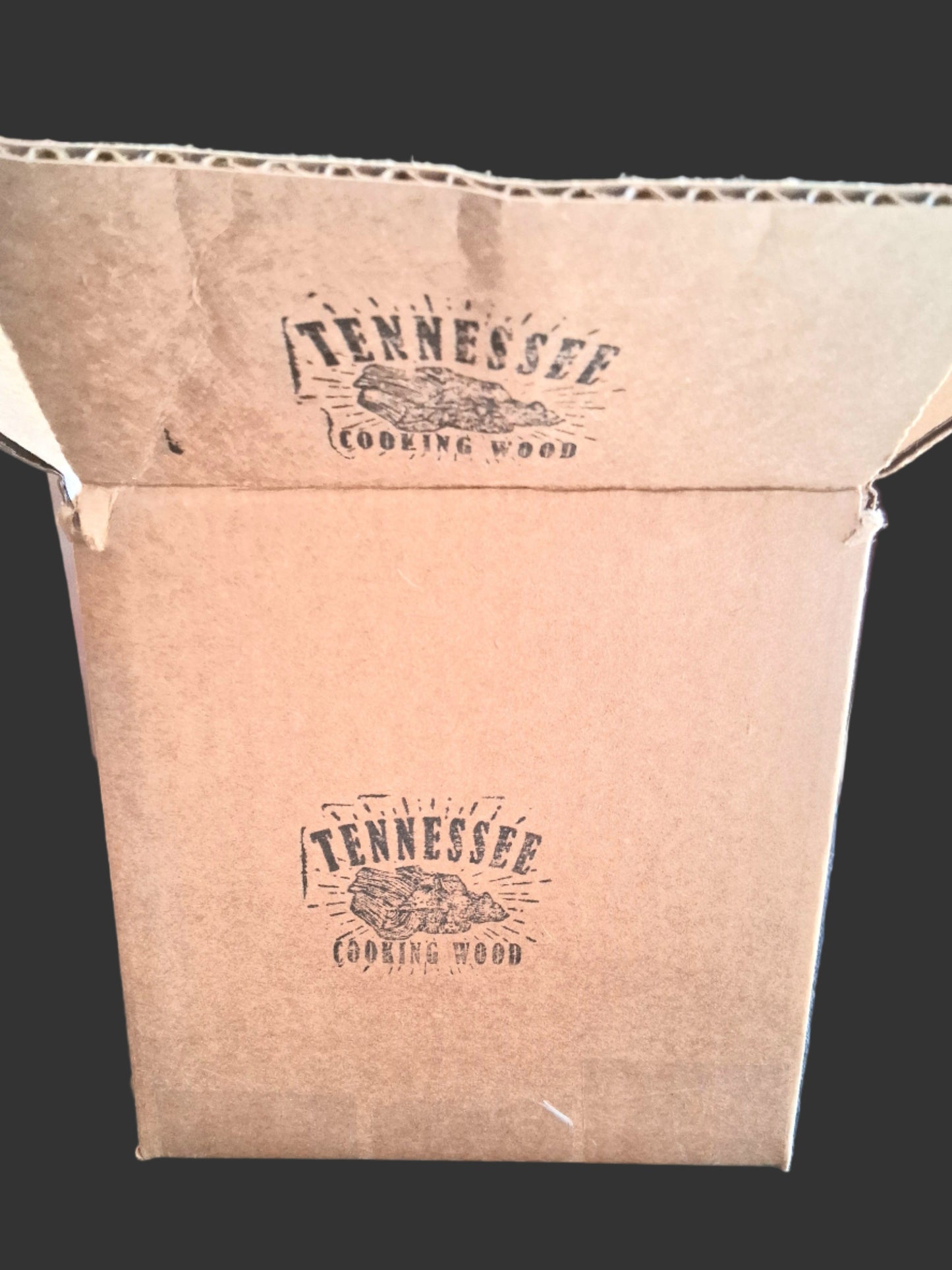 Cardboard box with 'Tennessee Cooking Wood' branding on a dark surface